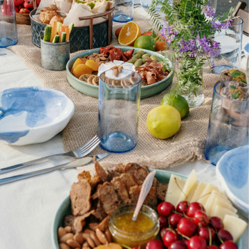 Tisch gedeckt mit Snacks und Getränken, dekoriert mit Blumen, im Freien bei Tageslicht.